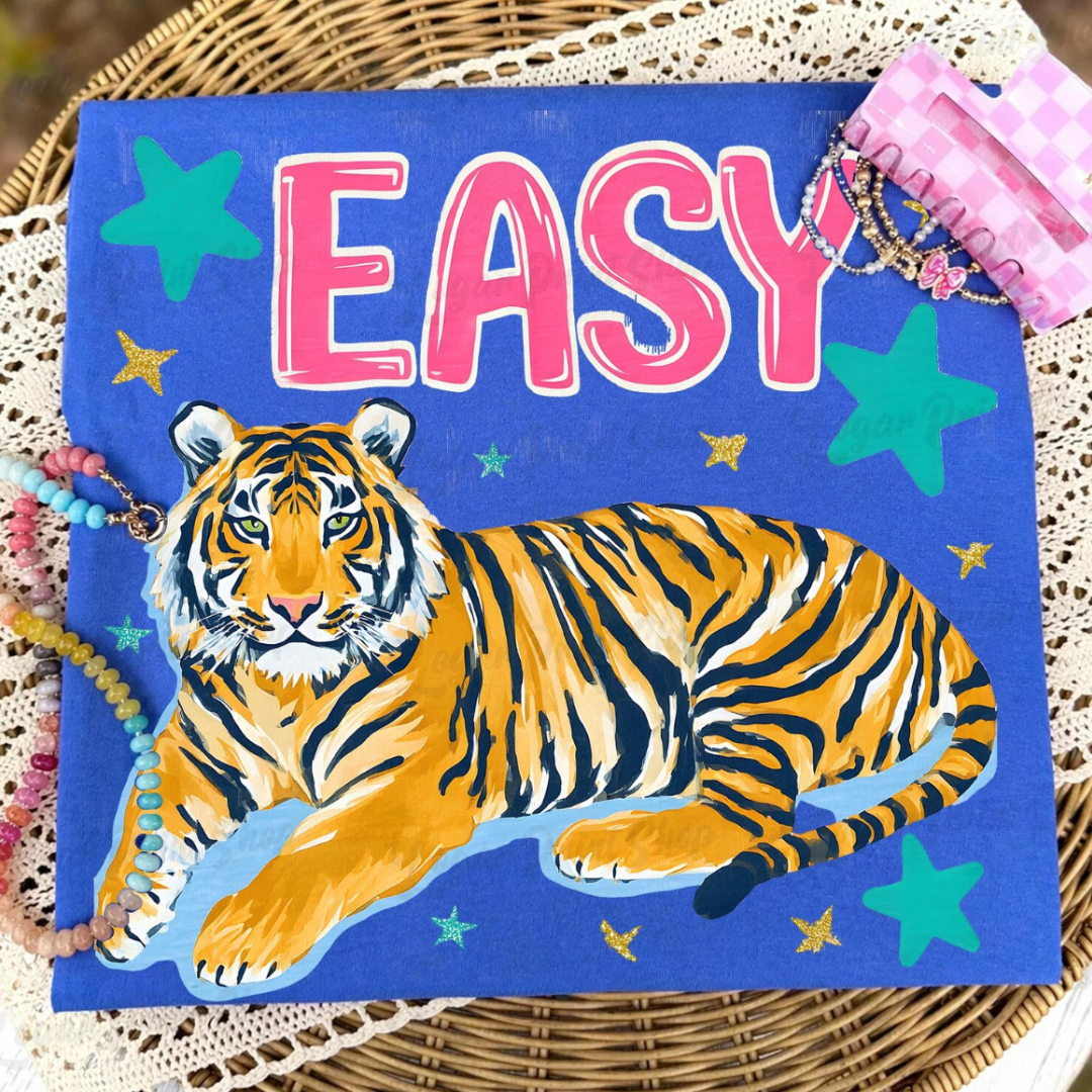 Royal blue graphic tee featuring a large tiger illustration with pink EASY lettering and colorful star accents.