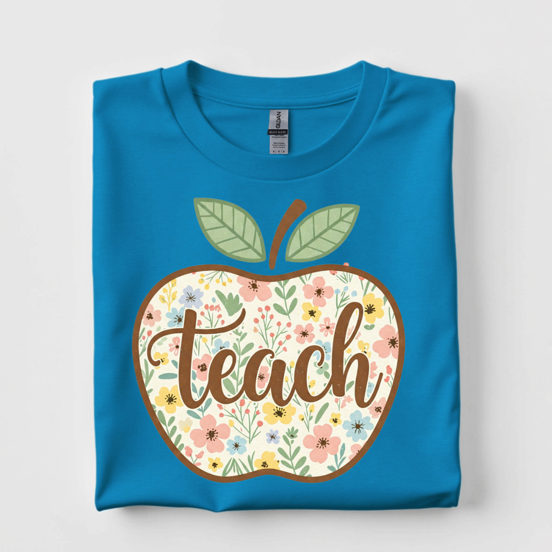 Bright blue graphic tee featuring a floral apple with the word "Teach" in elegant script lettering.