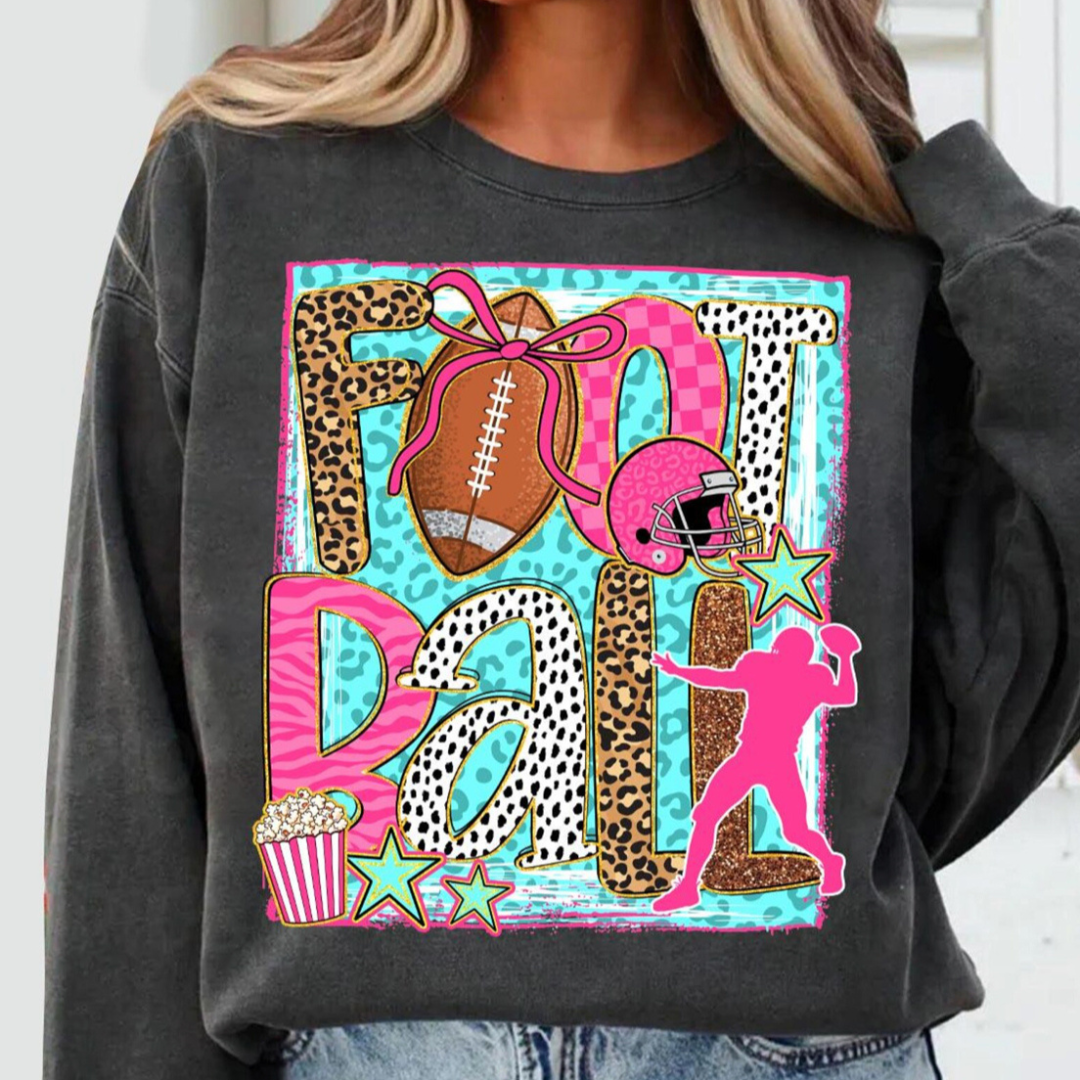 Charcoal sweatshirt featuring a colorful Football graphic with leopard print, checkered patterns, football, helmet, quarterback silhouette, stars, and popcorn for a fun game day look.