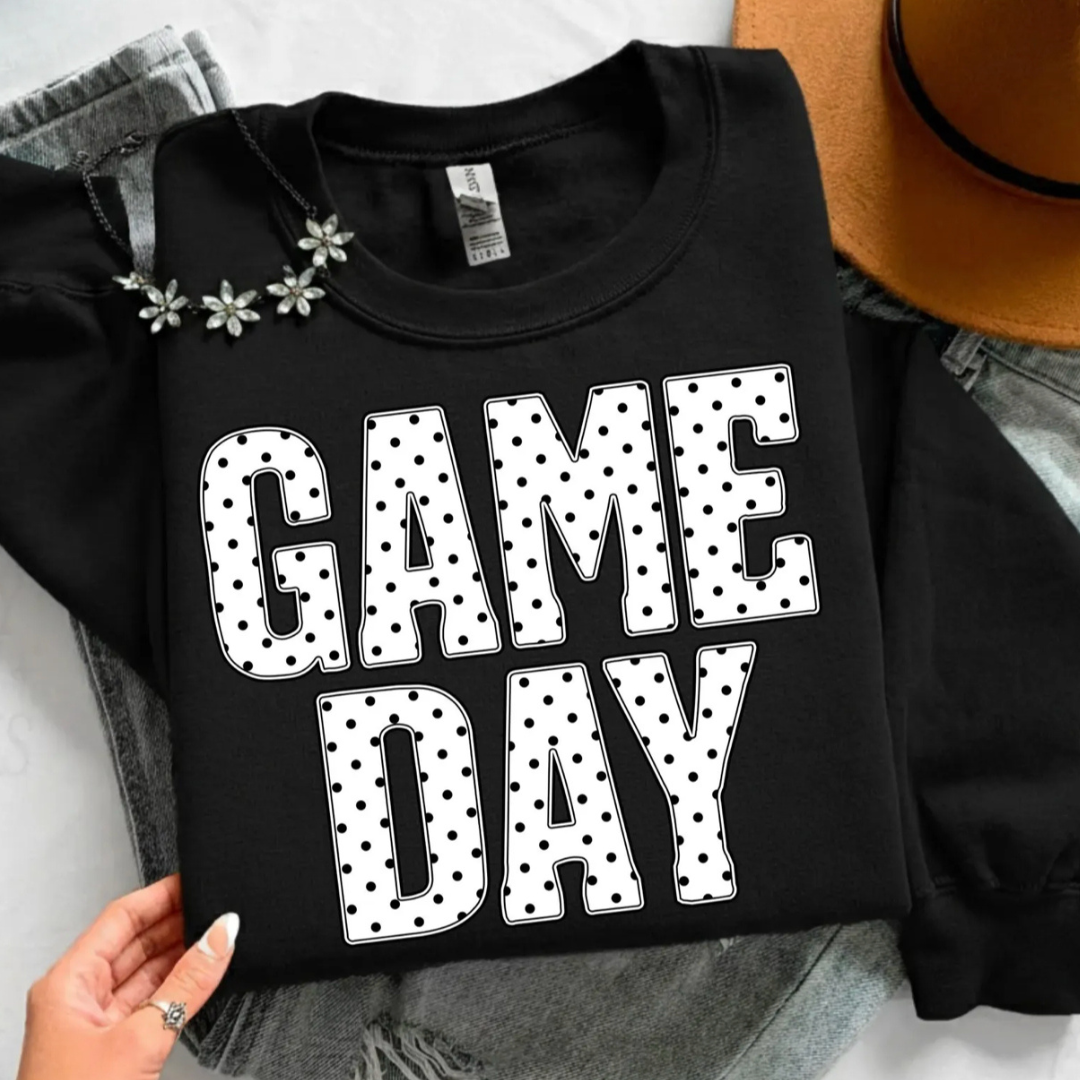 Black graphic tee featuring oversized white "Game Day" lettering with a black polka dot pattern.