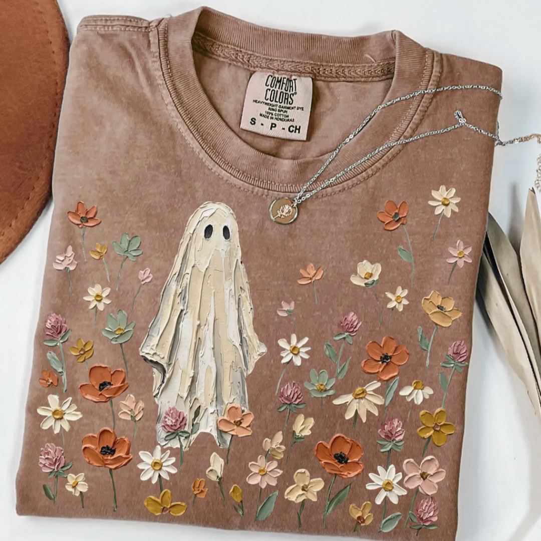 Mocha brown Comfort Colors graphic tee featuring a vintage ghost standing among soft neutral wildflowers in a whimsical fall-inspired design.