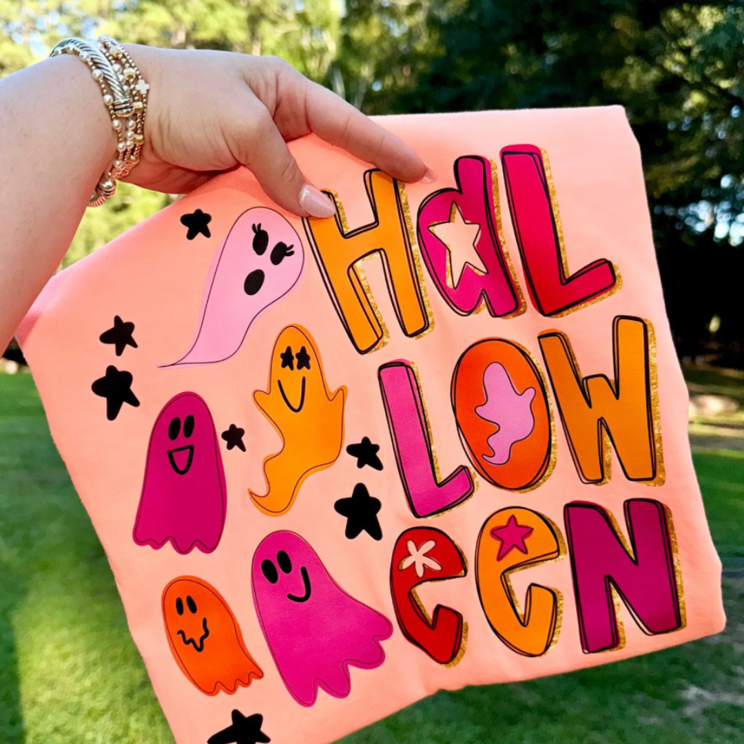 Peach Halloween graphic tee featuring colorful retro ghosts, bold "Halloween" lettering, and playful star accents.