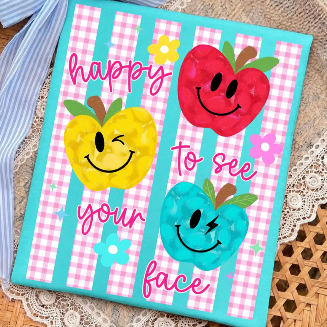 Turquoise teacher graphic tee featuring smiling colorful apples with pink gingham stripes and the phrase "Happy to See Your Face."