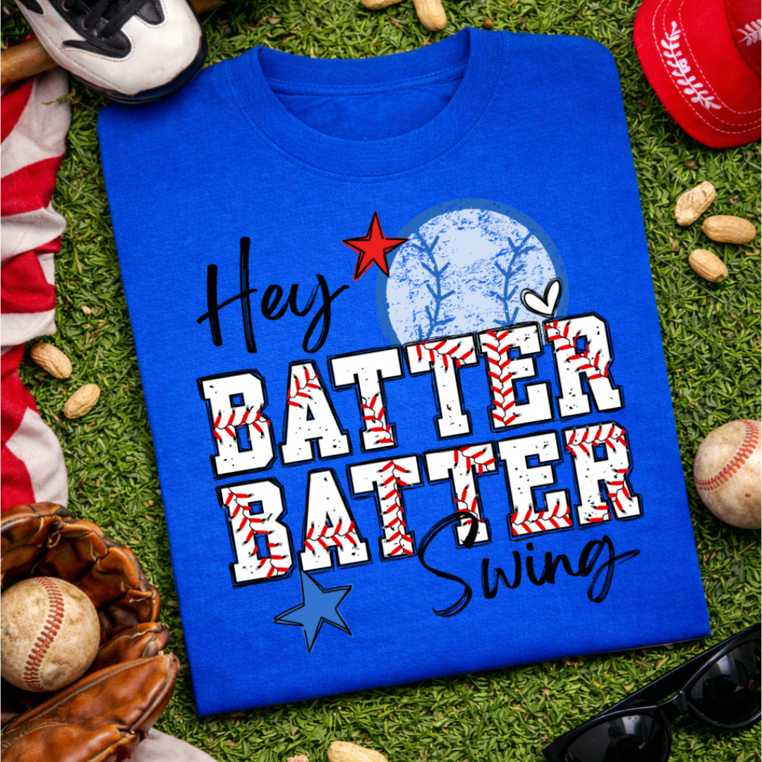Royal blue graphic tee featuring the phrase "Hey Batter Batter Swing" with baseball-stitched lettering, a distressed baseball graphic, and red, white, and blue star accents.