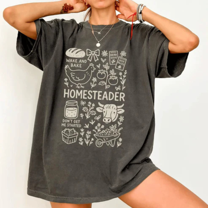 Comfort Colors graphic t-shirt available in pepper and espresso featuring a vintage Homesteader design with farmhouse and garden-inspired illustrations.