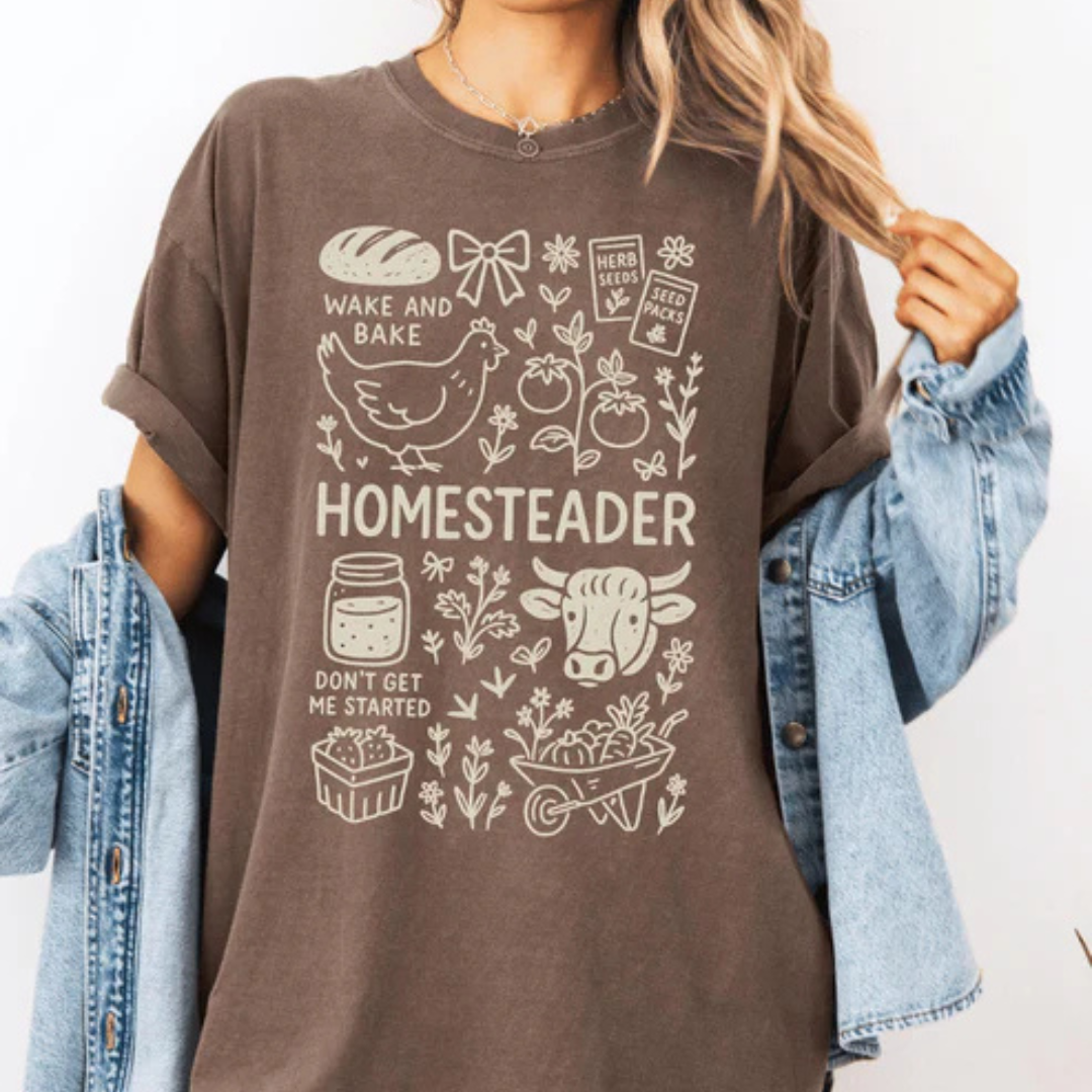 Comfort Colors graphic t-shirt available in pepper and espresso featuring a vintage Homesteader design with farmhouse and garden-inspired illustrations.