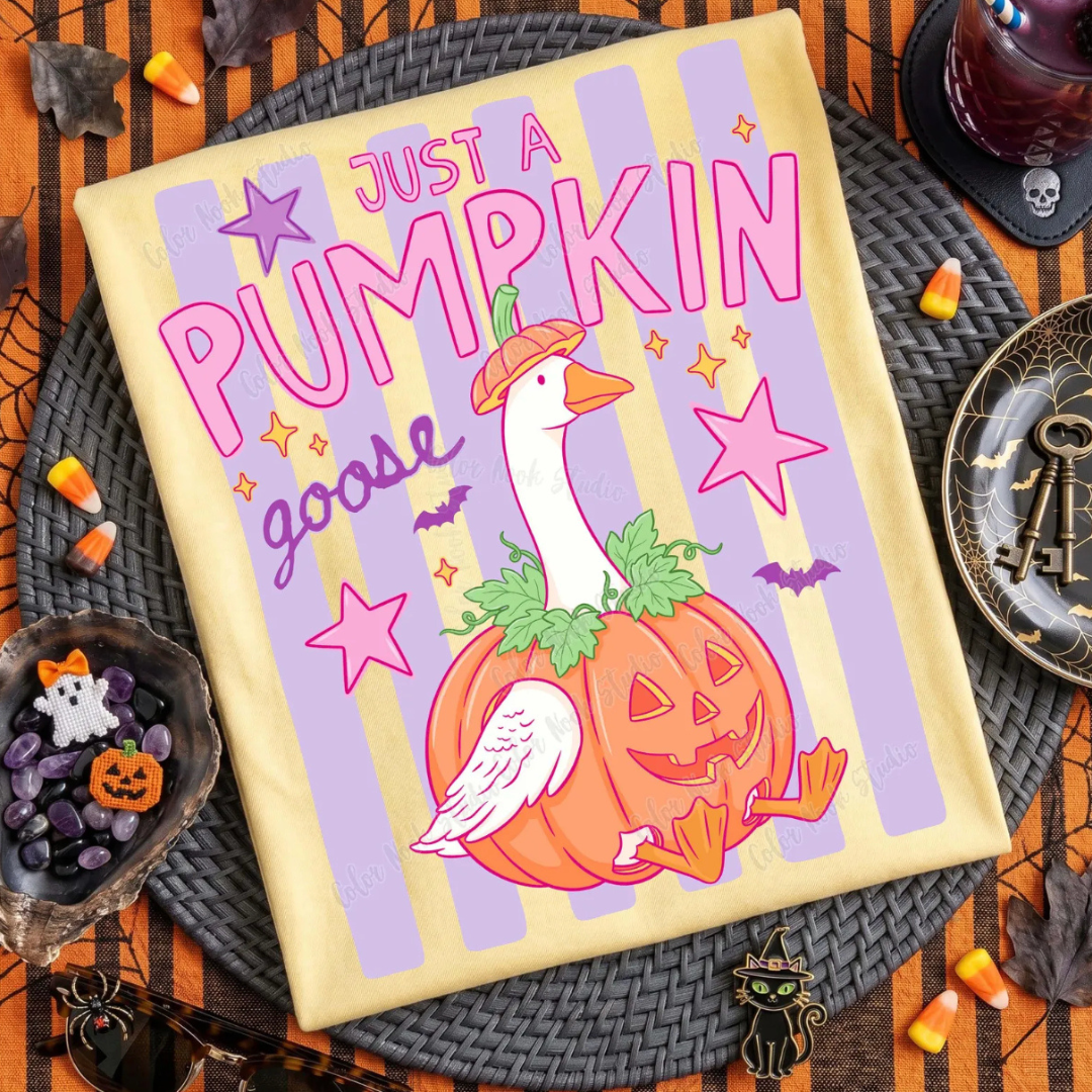 Butter yellow Halloween graphic tee featuring a goose dressed as a pumpkin with lavender stripes, pink lettering, stars, and bats reading "Just a Pumpkin Goose."
