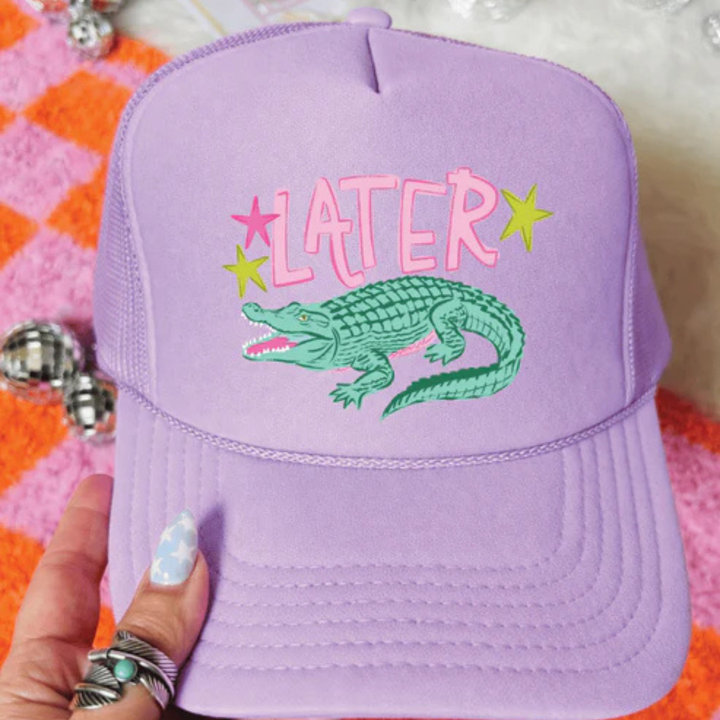 Lavender foam trucker hat featuring a Later Gator graphic with a hand-drawn alligator and colorful retro-inspired accents.
