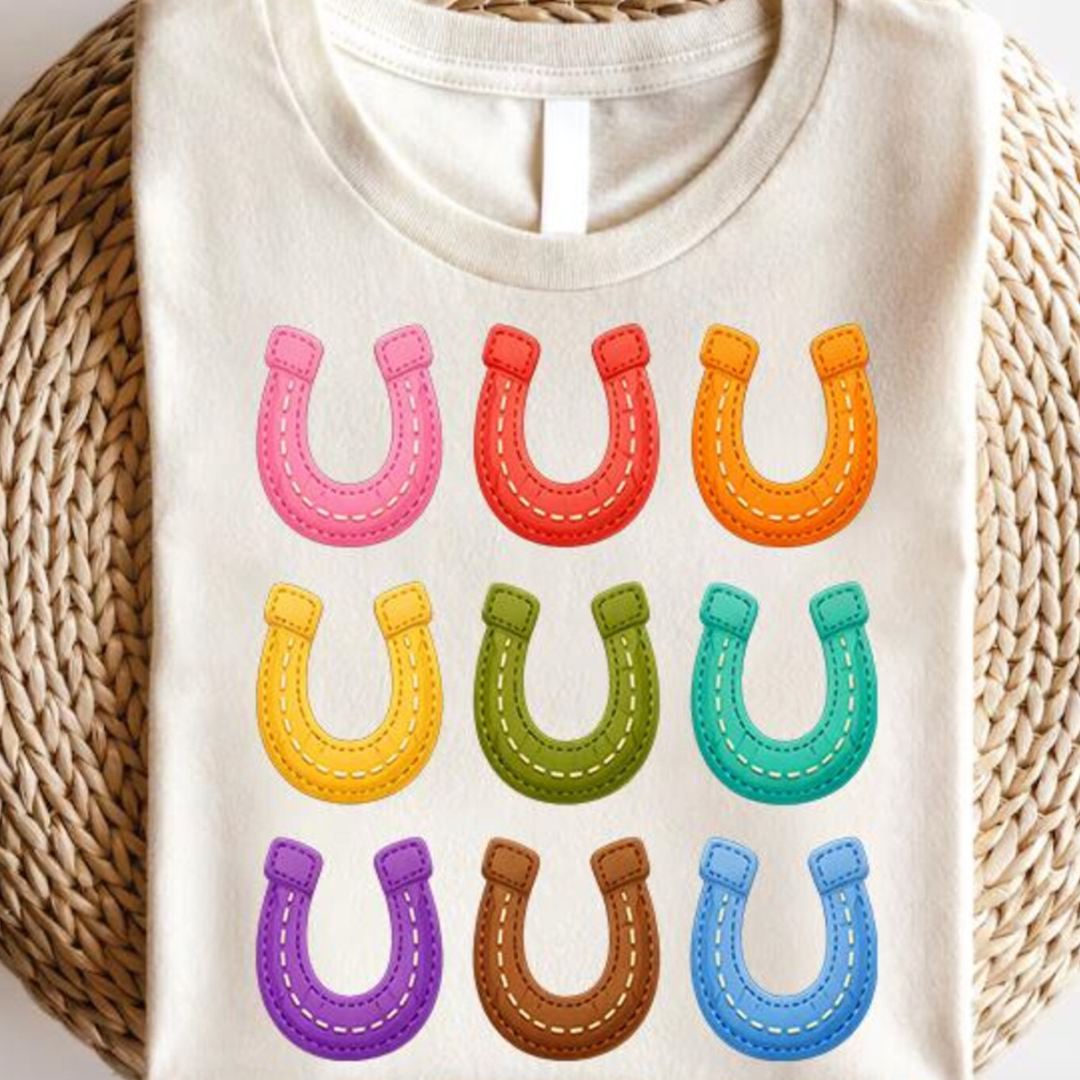 Natural beige graphic tee featuring a colorful grid of stitched horseshoe graphics in bright western-inspired colors.