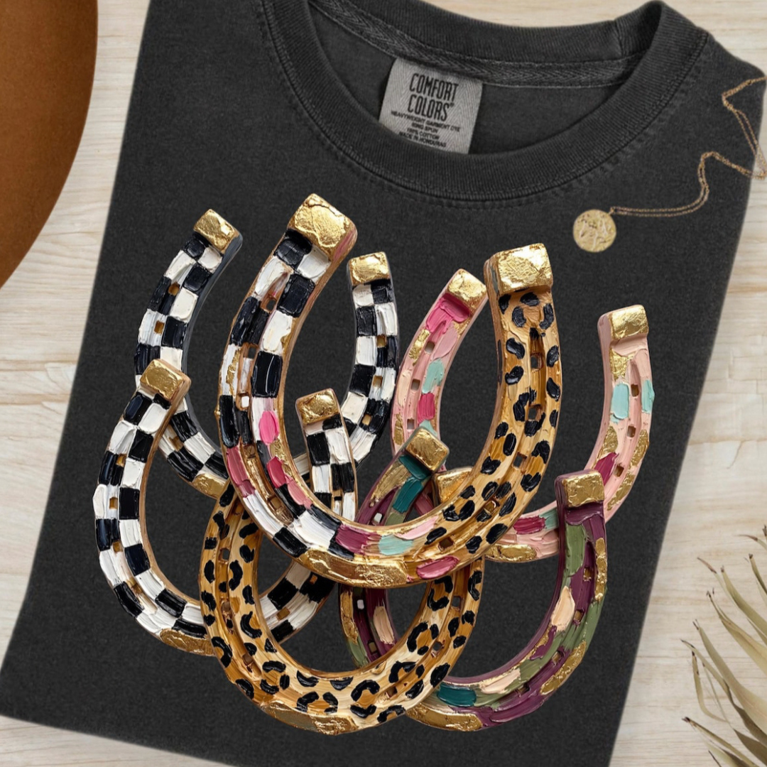 Pepper black graphic tee featuring colorful horseshoes with checkered, leopard, floral, and gold western-inspired details.