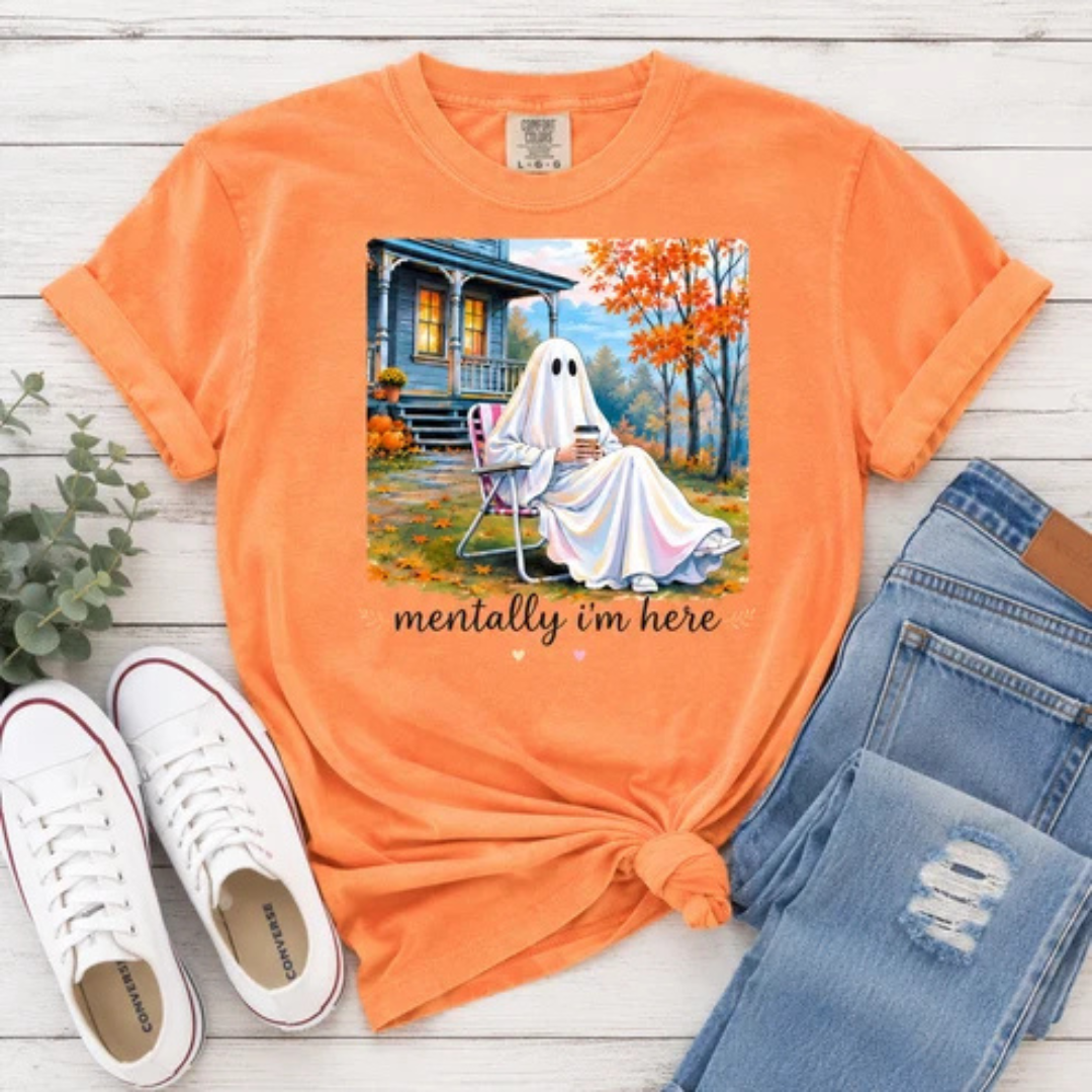 Orange graphic tee featuring a cozy ghost sitting in a lawn chair with a warm drink on a fall porch with colorful autumn trees and the phrase "Mentally I&