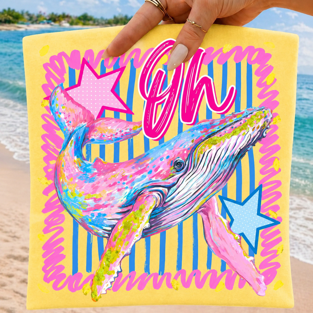 Butter yellow graphic tee featuring a colorful painted whale with pink and blue striped accents and the phrase "Oh Whale."