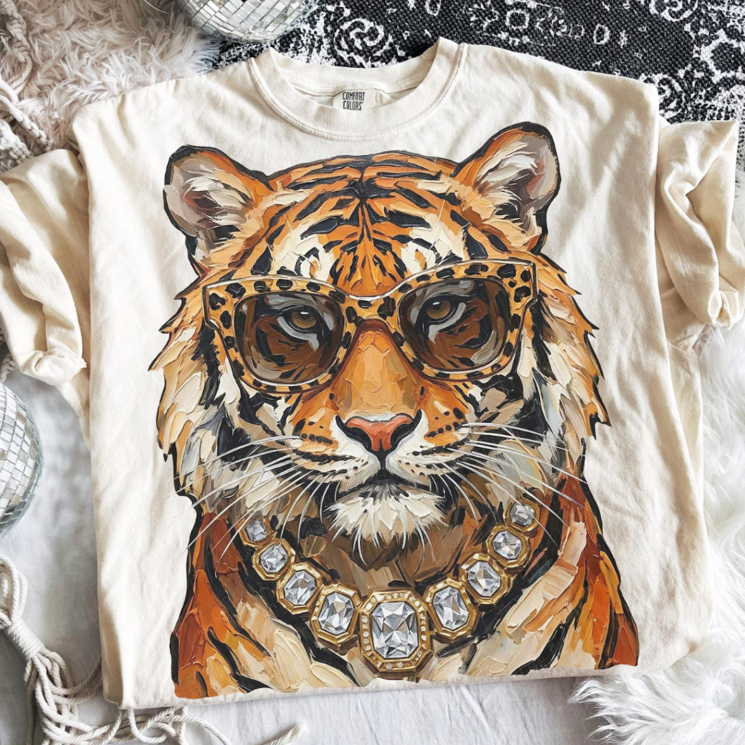 Natural beige graphic tee featuring a fashionable tiger wearing leopard-print sunglasses and a crystal-inspired statement necklace.