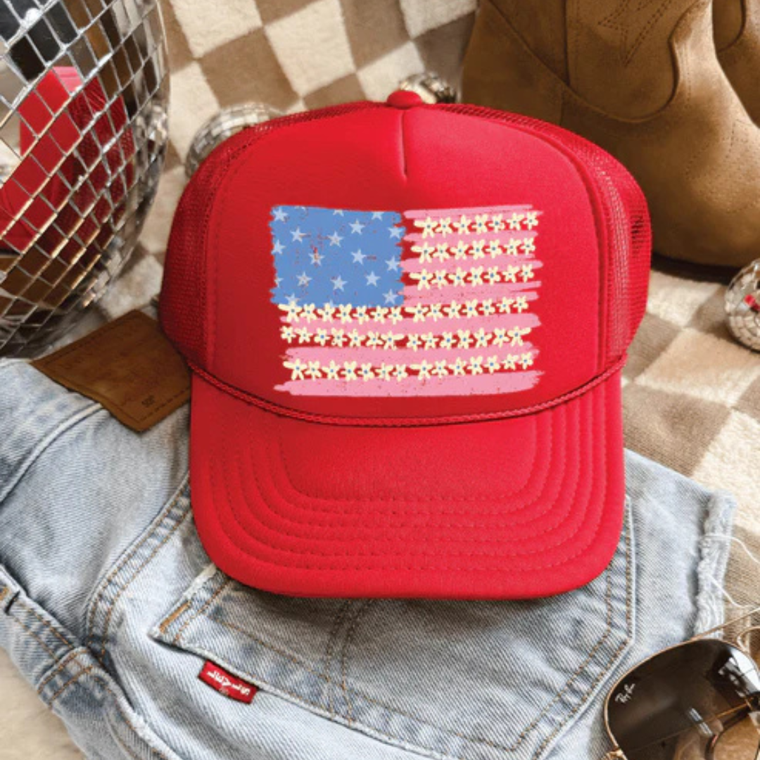 Red foam trucker hat featuring a floral American flag graphic with mesh back and adjustable snapback closure.