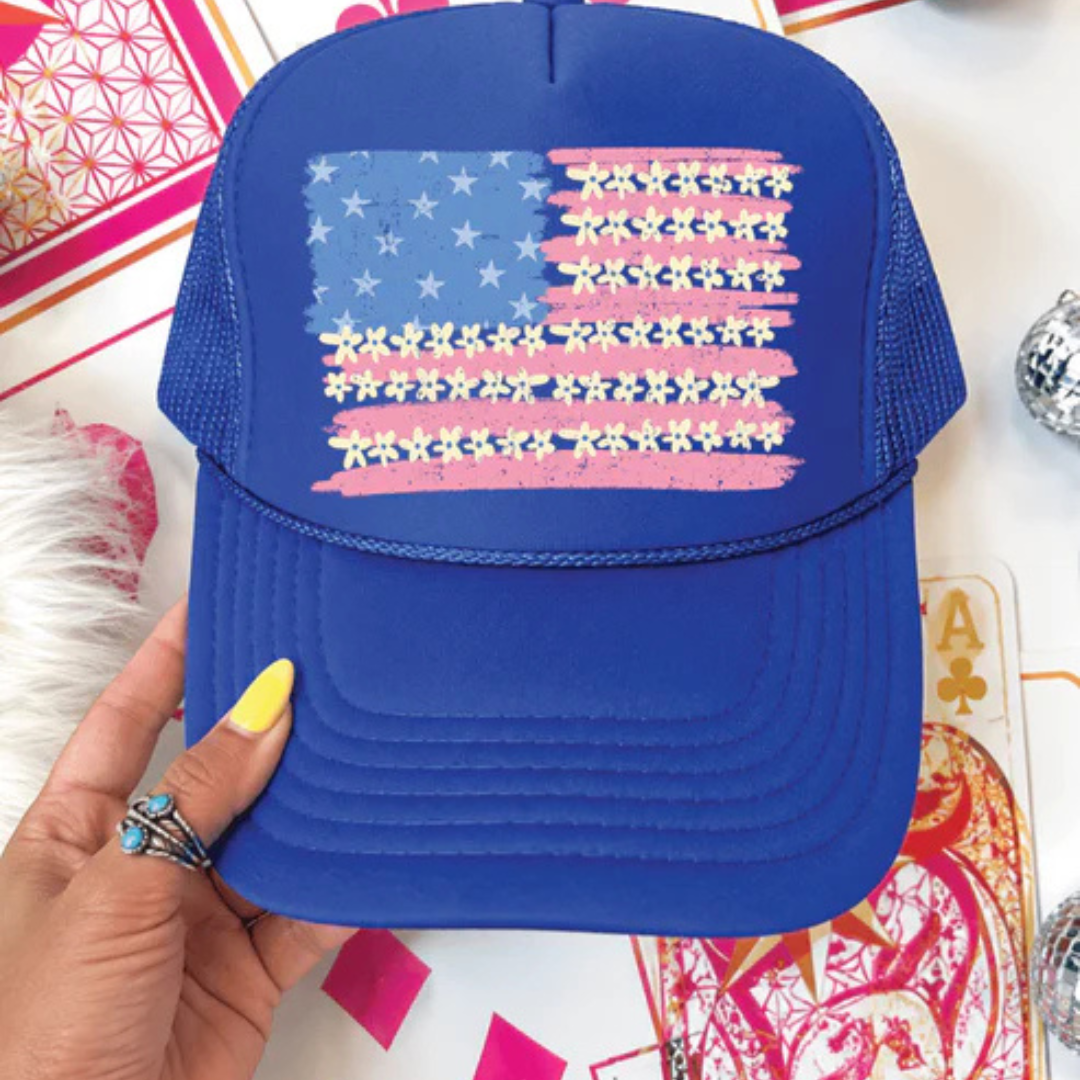 Royal blue foam trucker hat featuring a floral American flag graphic with patriotic red, white, and blue details.