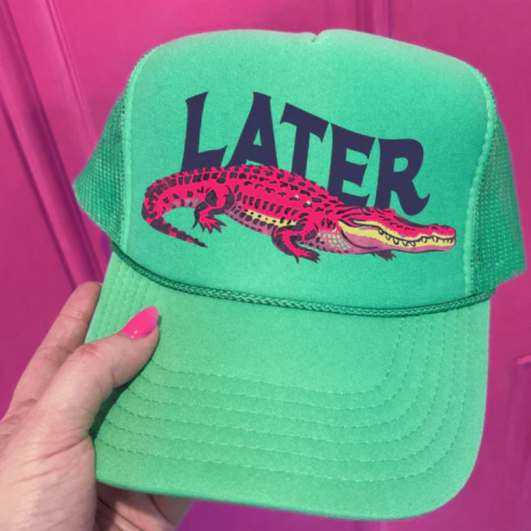 Cactus green trucker hat featuring a bright pink alligator graphic and the phrase "Later Gator."