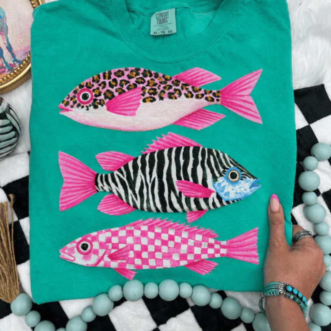 Island green graphic tee featuring three colorful tropical fish with leopard, zebra, and pink checkered patterns.