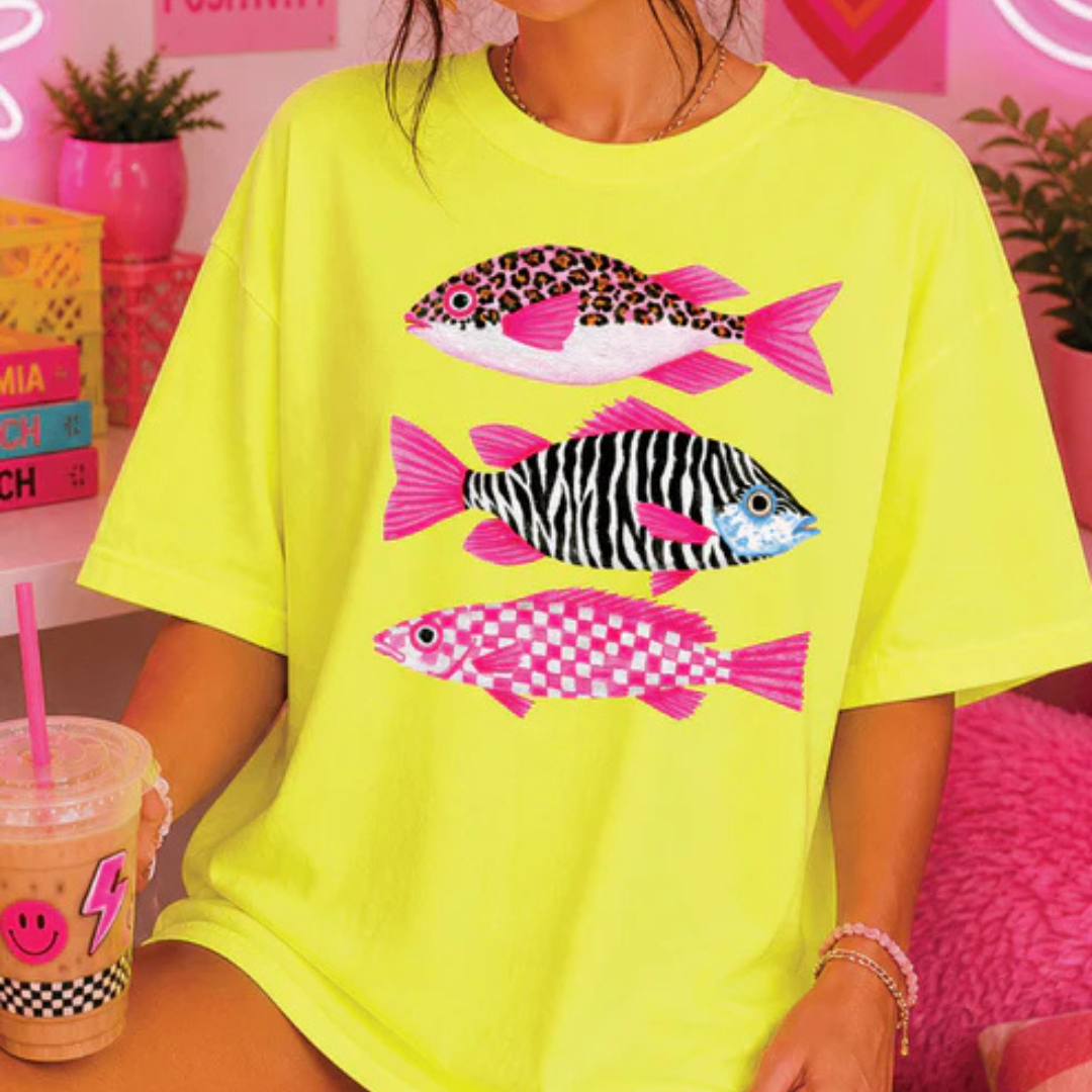 Neon yellow graphic tee featuring three colorful tropical fish with leopard, zebra, and pink checkered patterns.