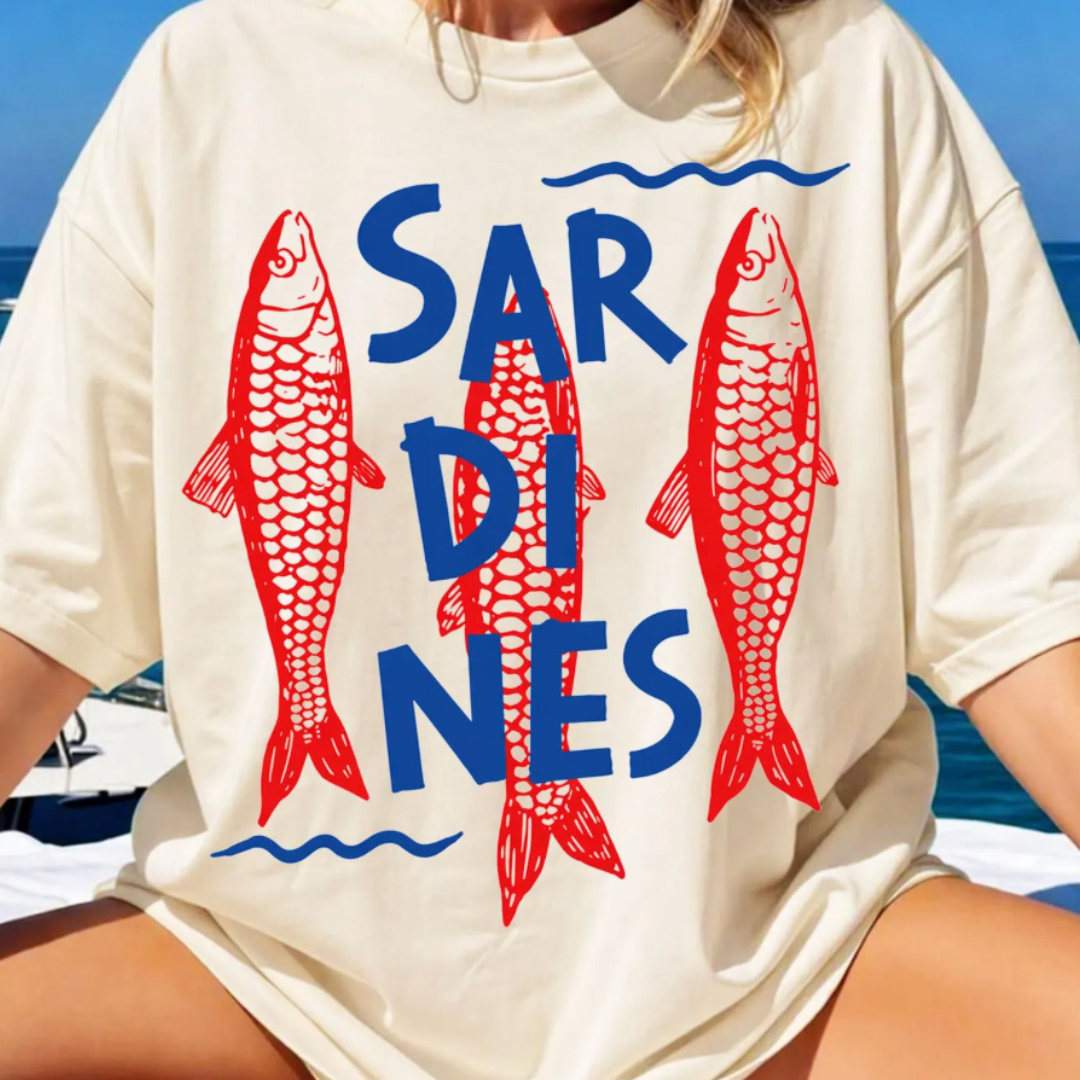 Natural graphic tee featuring bold navy "Sardines" lettering layered over vintage-style red fish illustrations with a coastal nautical aesthetic.