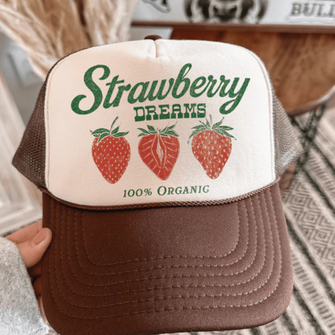 Brown and cream foam trucker hat featuring a vintage Strawberry Dreams graphic with strawberries and 100% Organic text.