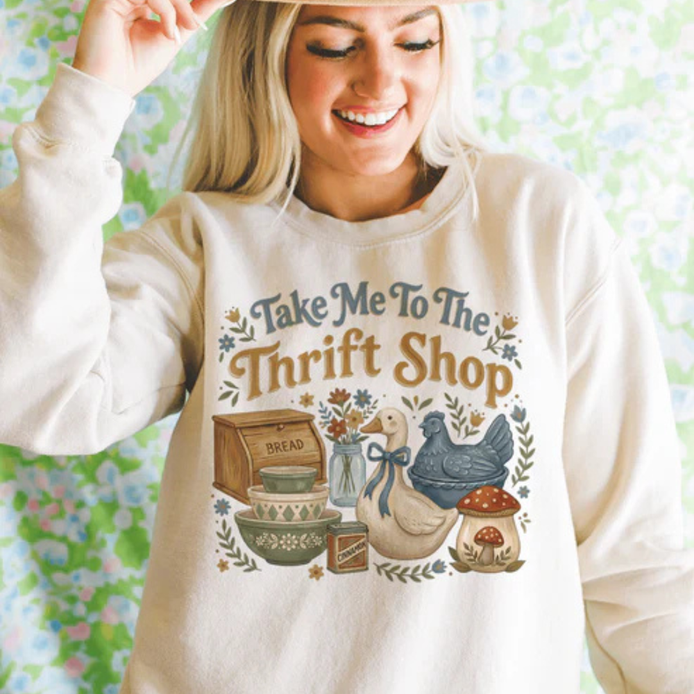 Cream graphic tee and sweatshirt featuring a vintage-inspired Take Me to the Thrift Shop design with cottage-style artwork and antique market charm.