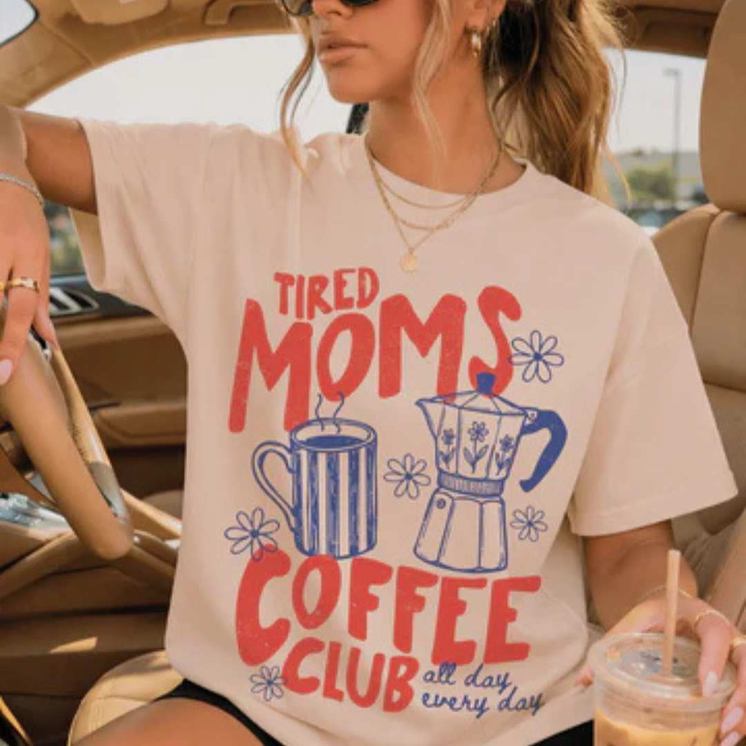 Cream graphic t-shirt featuring a Tired Moms Coffee Club design with vintage coffee-themed artwork and floral accents.