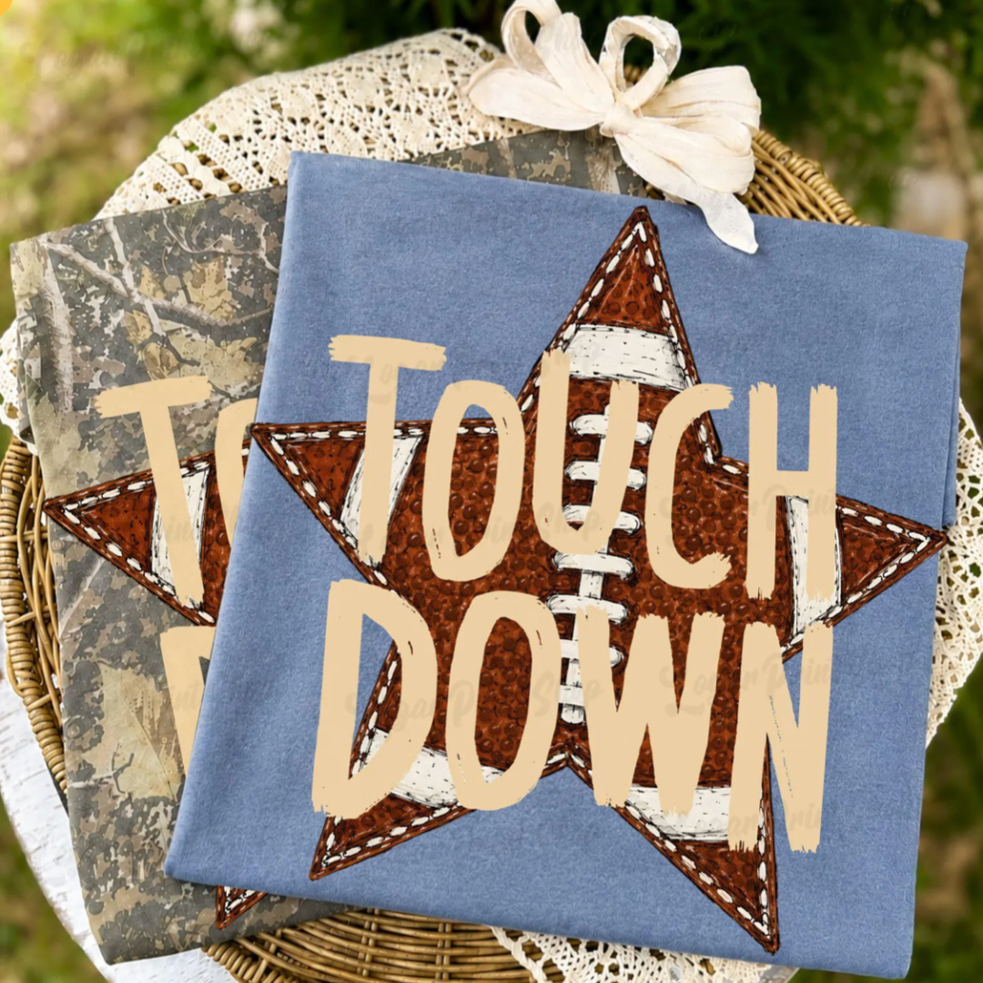 Blue graphic tee featuring a stitched football star with bold "Touch Down" lettering in a vintage-inspired design.