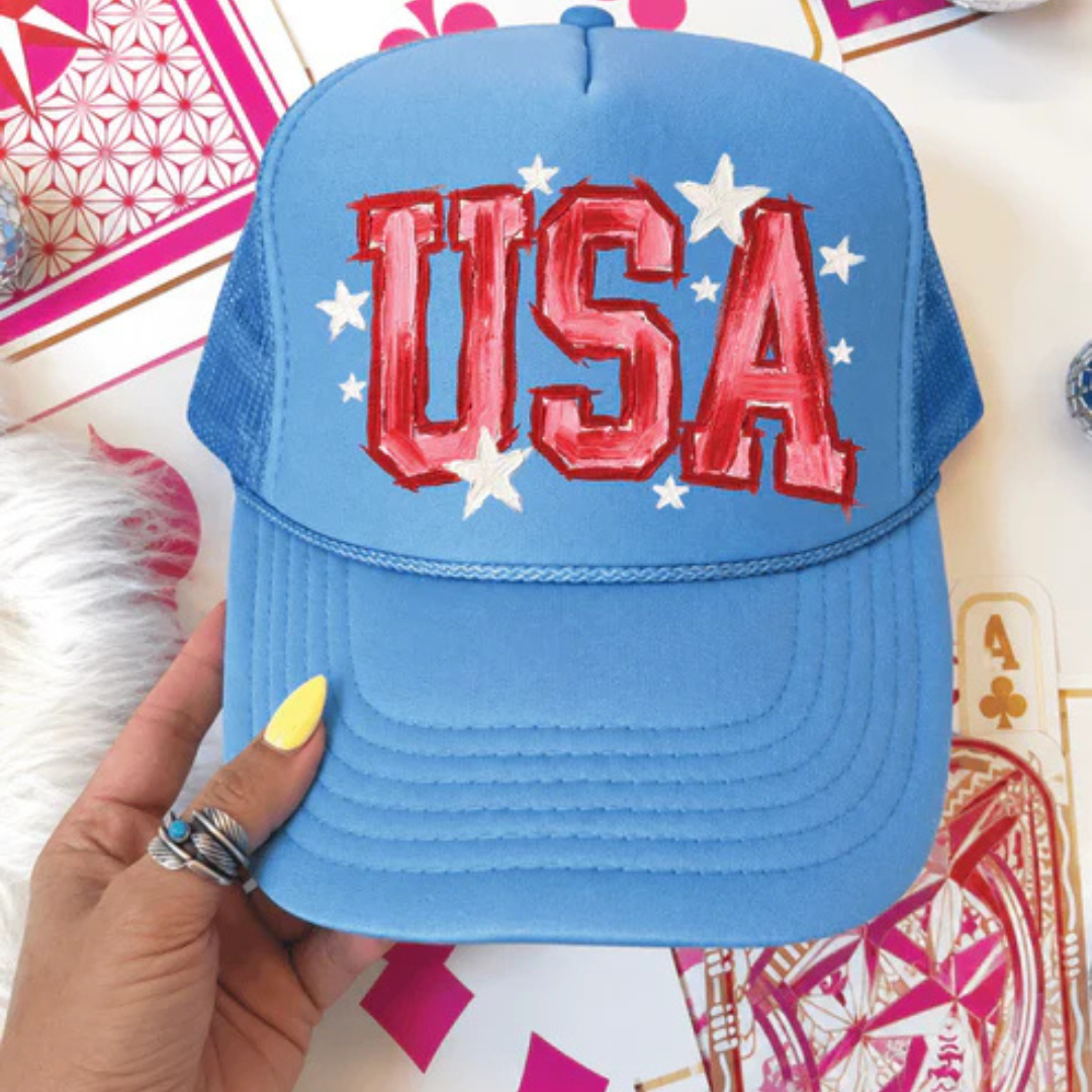 Carolina blue foam trucker hat featuring oversized USA lettering with white star accents in a patriotic design.