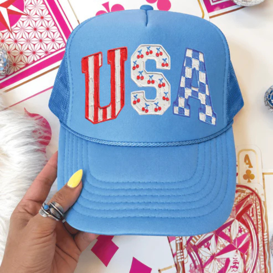 Carolina blue foam trucker hat featuring USA lettering with cherry and blue checkered patriotic accents