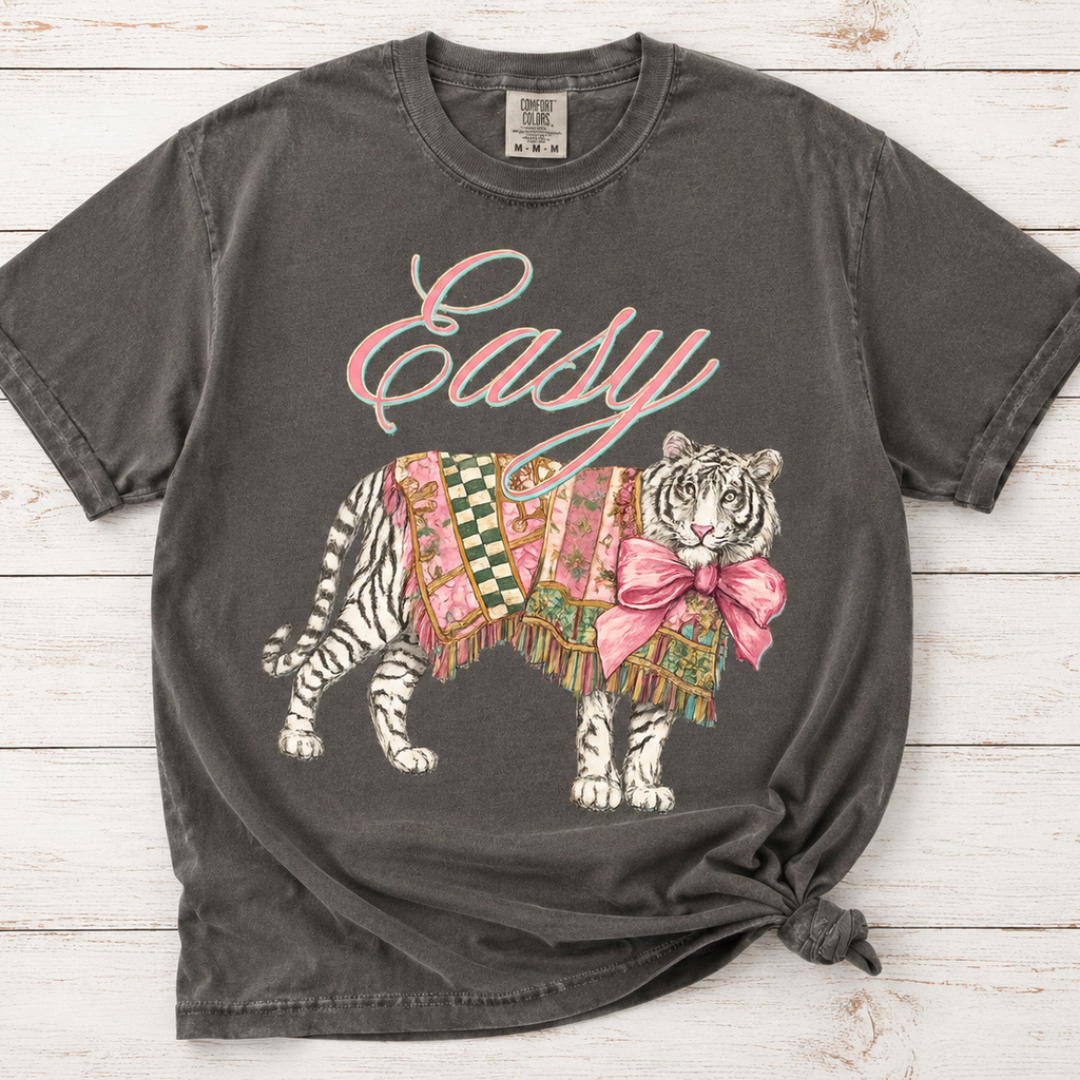 Pepper gray Comfort Colors graphic tee featuring a tiger wearing a colorful patchwork blanket with a pink bow and Easy script lettering.