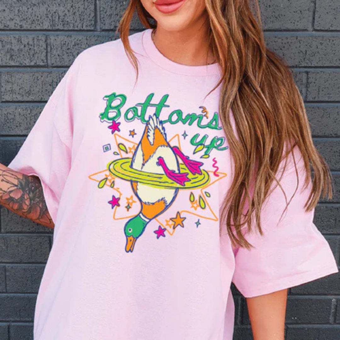 Graphic t-shirt featuring a colorful upside-down mallard duck splashing into water with Bottoms Up text in multiple color options.