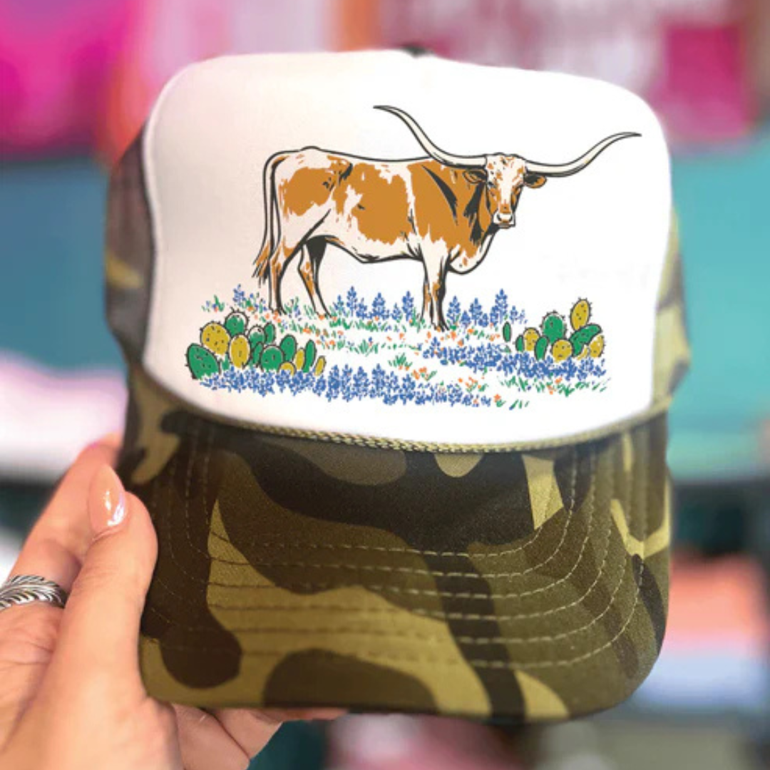 Camouflage-patterned cap with a cow and flowers design on a white background
