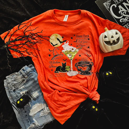 Orange Halloween-themed t-shirt with graphics on a dark surface with accessories.