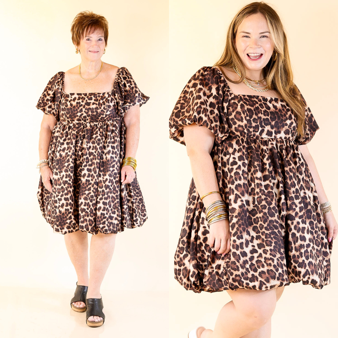 Two women wearing cheetah print dresses on a plain background