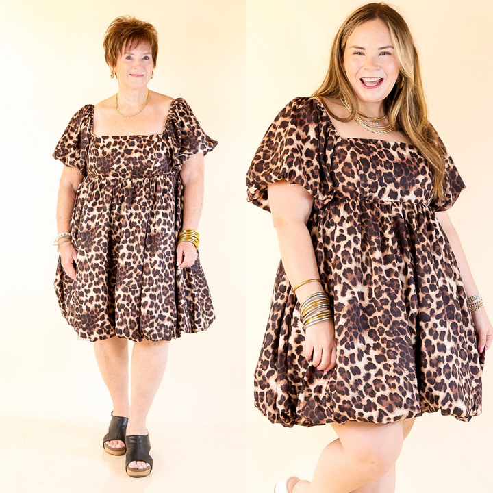 Two women wearing cheetah print dresses on a plain background