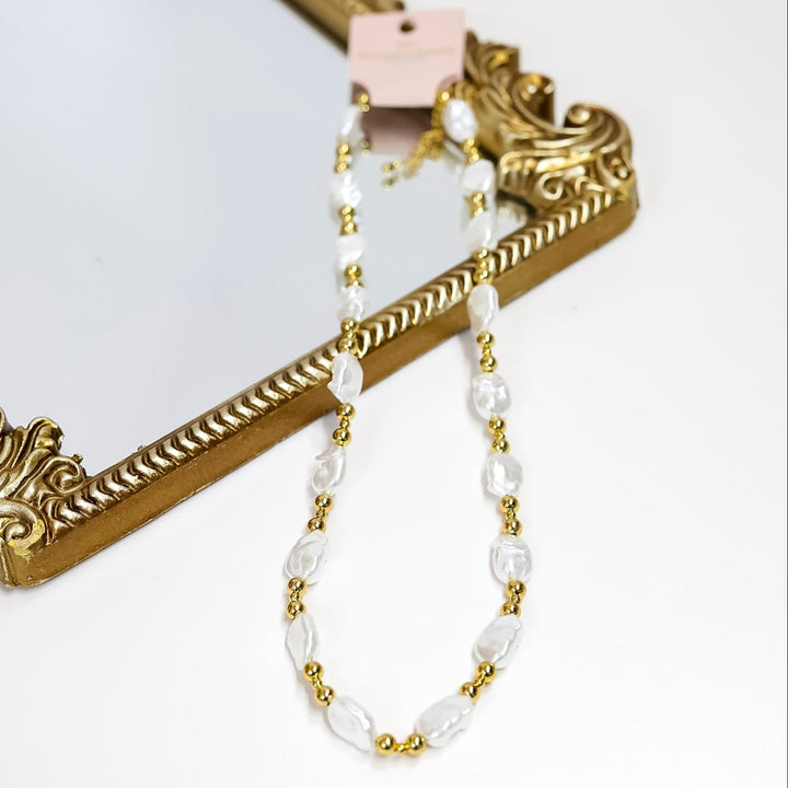Pearl and gold beaded necklace on a white background with a decorative gold frame.