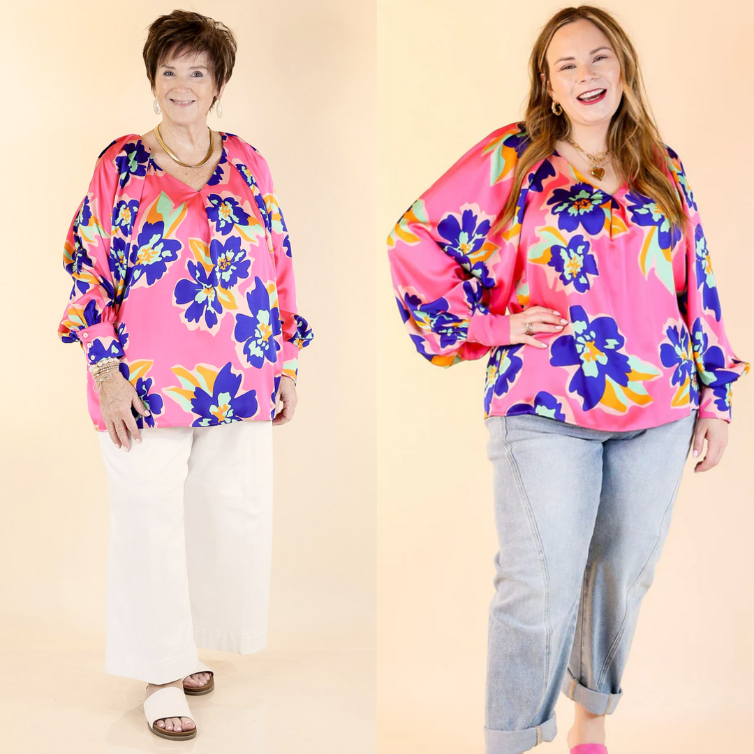 Cut with a flattering V-neckline and pleated shoulder detail, the versatile piece is finished with a blue, green, and orange floral print. Sizes small to plus sizes.