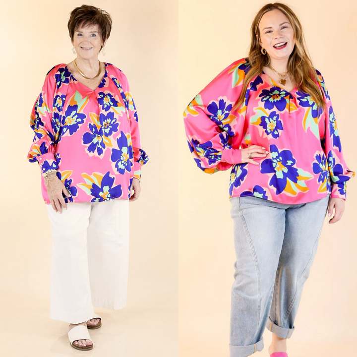 Cut with a flattering V-neckline and pleated shoulder detail, the versatile piece is finished with a blue, green, and orange floral print. Sizes small to plus sizes.