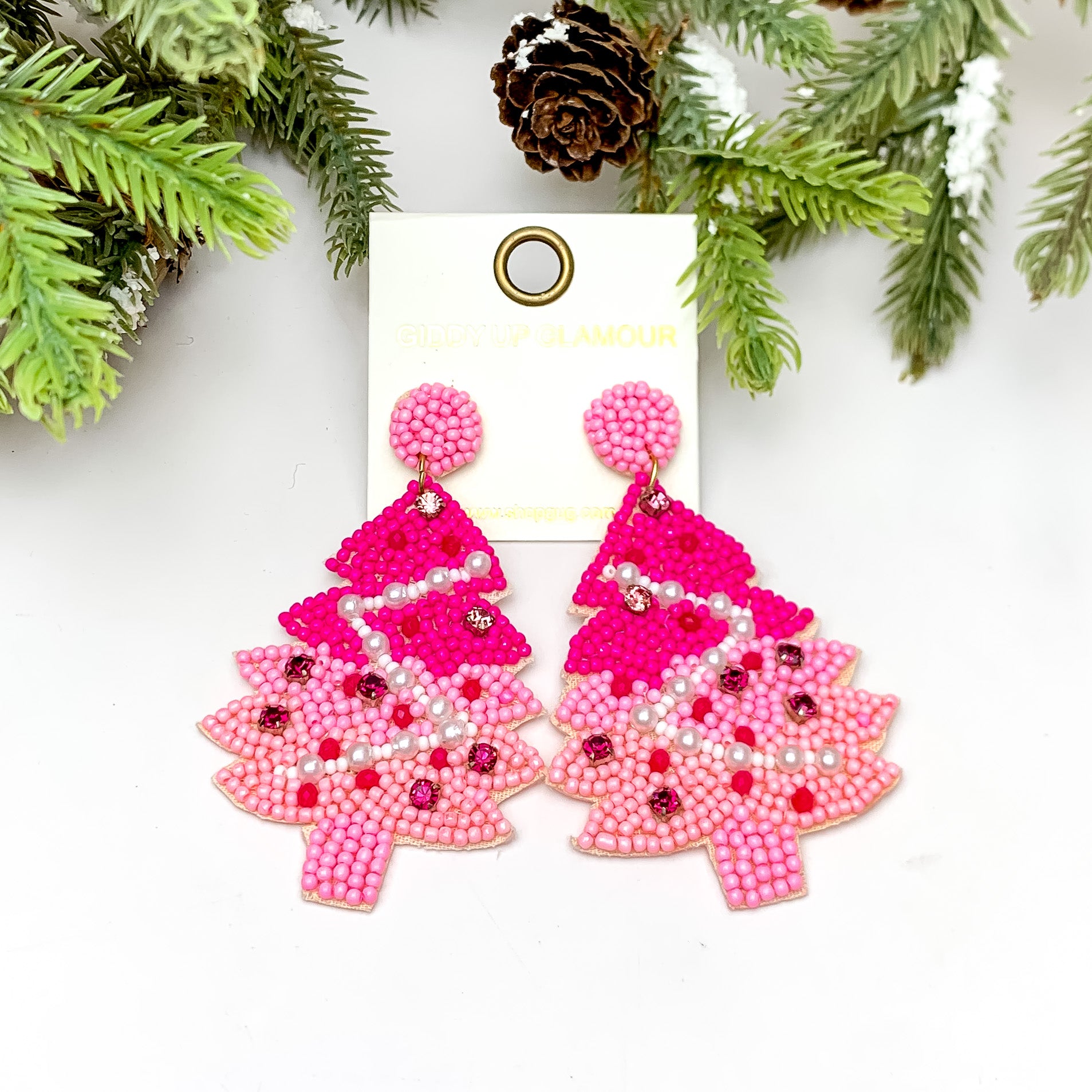 Beaded Christmas Tree Earrings in Pink Tones. These earrings are pictured on a white background with a tree and pine cones at the top.