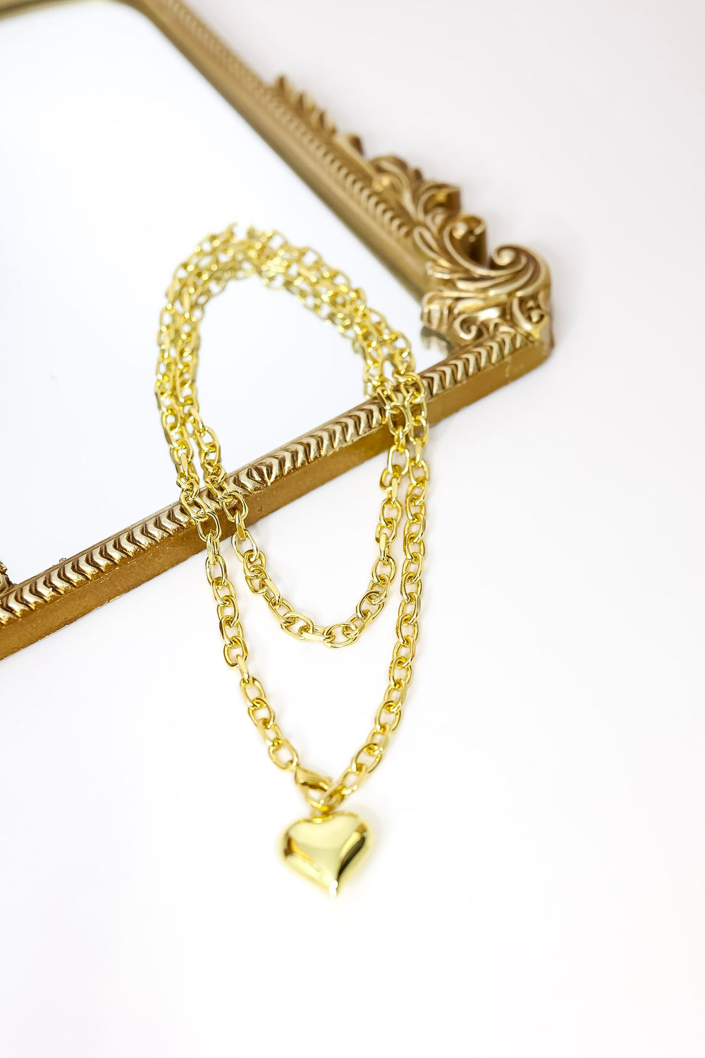 Gold chain necklace with a heart pendant on a white background