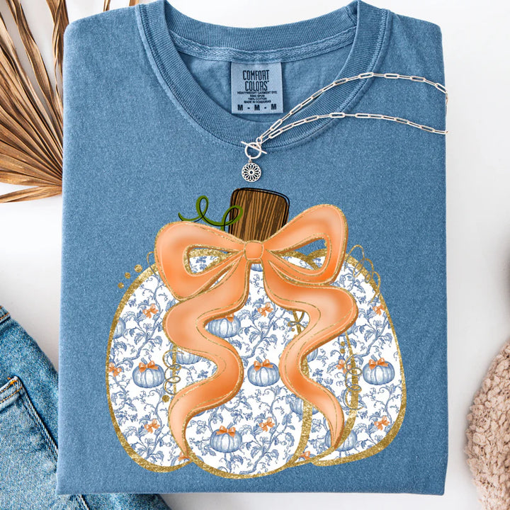 Blue t-shirt with a decorative pumpkin design featuring a bow on a white background