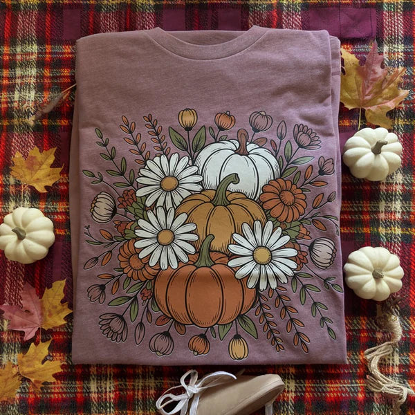 Purple t-shirt with pumpkins and flowers design on a plaid fabric background