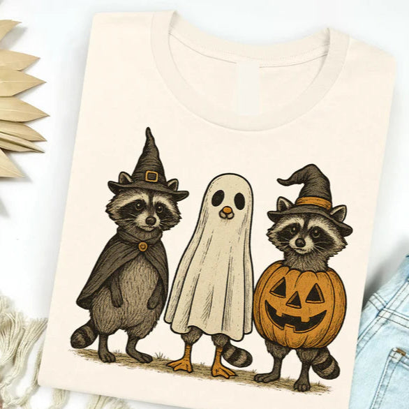 T-shirt with Halloween-themed design of raccoons and ghost on a white background