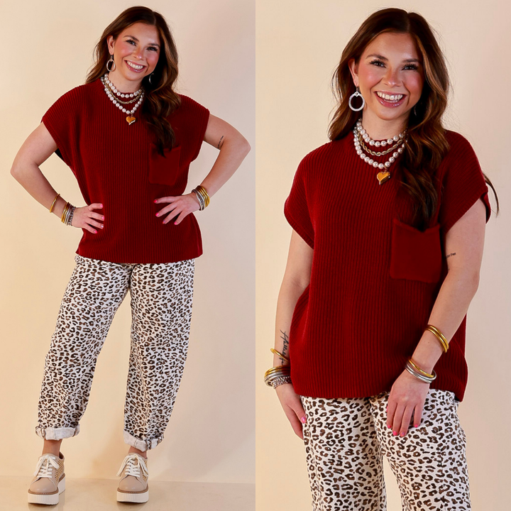 Model is wearing Cap Sleeve Sweater with Front Pocket in Maroon with Jeans against a beige backdrop. 