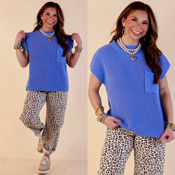 Model is wearing Cap Sleeve Sweater with Front Pocket in Periwinkle Blue with Jeans against a beige backdrop. 