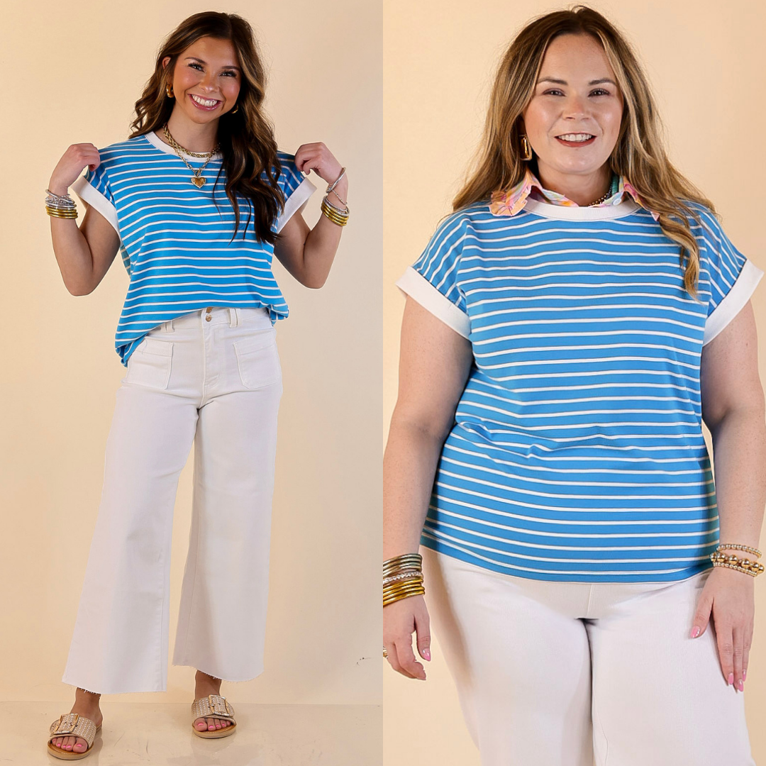 Two women wearing blue and white striped shirts with white pants against a beige background