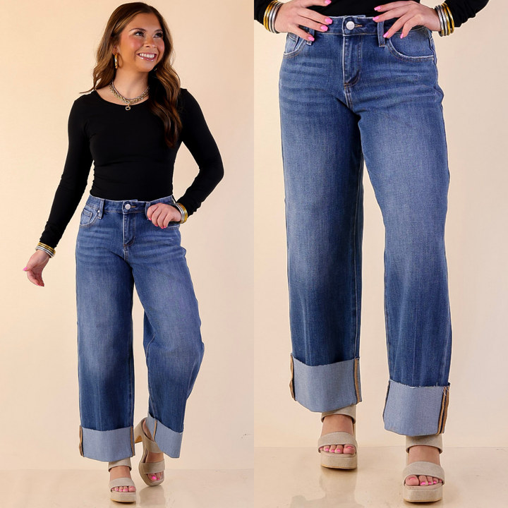 Model is wearing Risen Straight Leg jeans with a cuff detail with a black top against a beige background. 