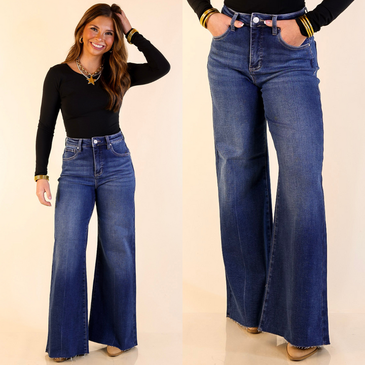 Woman wearing Wide Leg Raw Hem Palazzo Jeans in Dark Wash on a plain background
