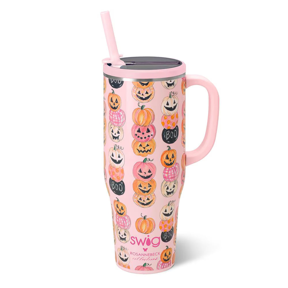 A pink handled travel tumbler with a lid and straw, decorated with a repeating pattern of orange, black, and white jack-o&