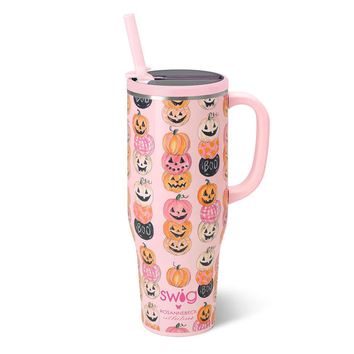 A pink handled travel tumbler with a lid and straw, decorated with a repeating pattern of orange, black, and white jack-o&